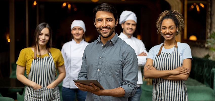 Business owner smiling with his staff at a restaurant