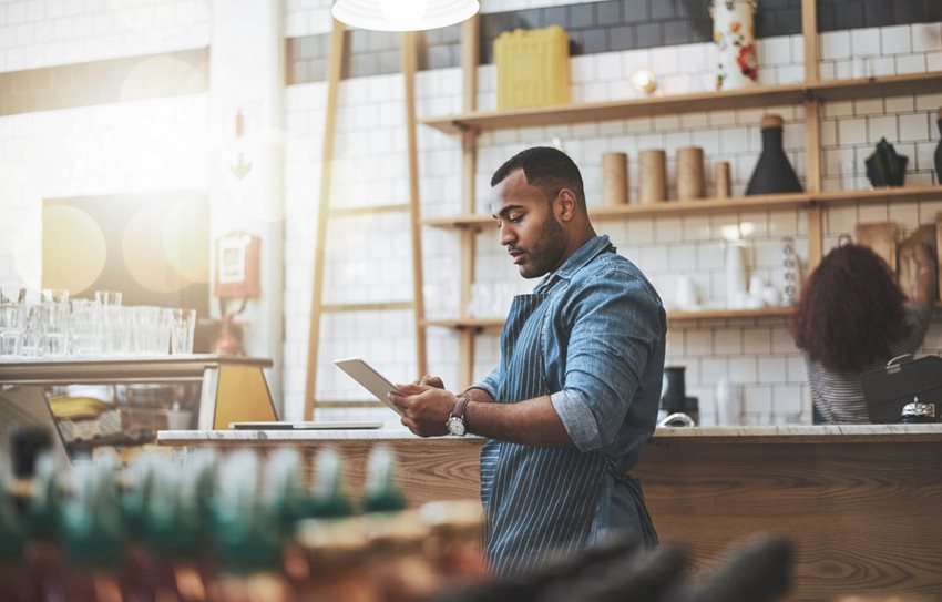 Restaurant worker in blue checking a digital tablet at work