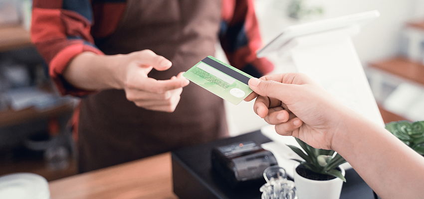 Close up of man's hand worker in cafe counter receiving payment via credit card from customer