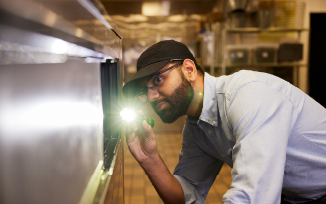 photo of a male inspecting kitchen equipment