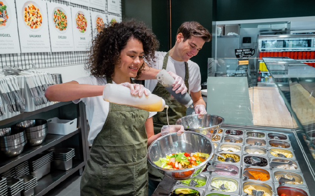 Photo of two restaurant workers preparing salads