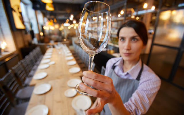 Photo of a waitress inspecting a clean wine glass